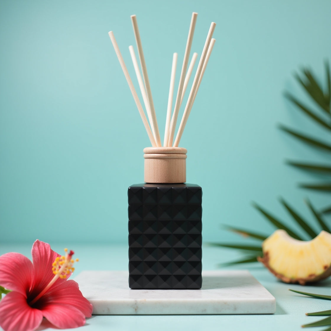 An Aloha Breeze tropical scented reed diffuser in a matte black bottle.
