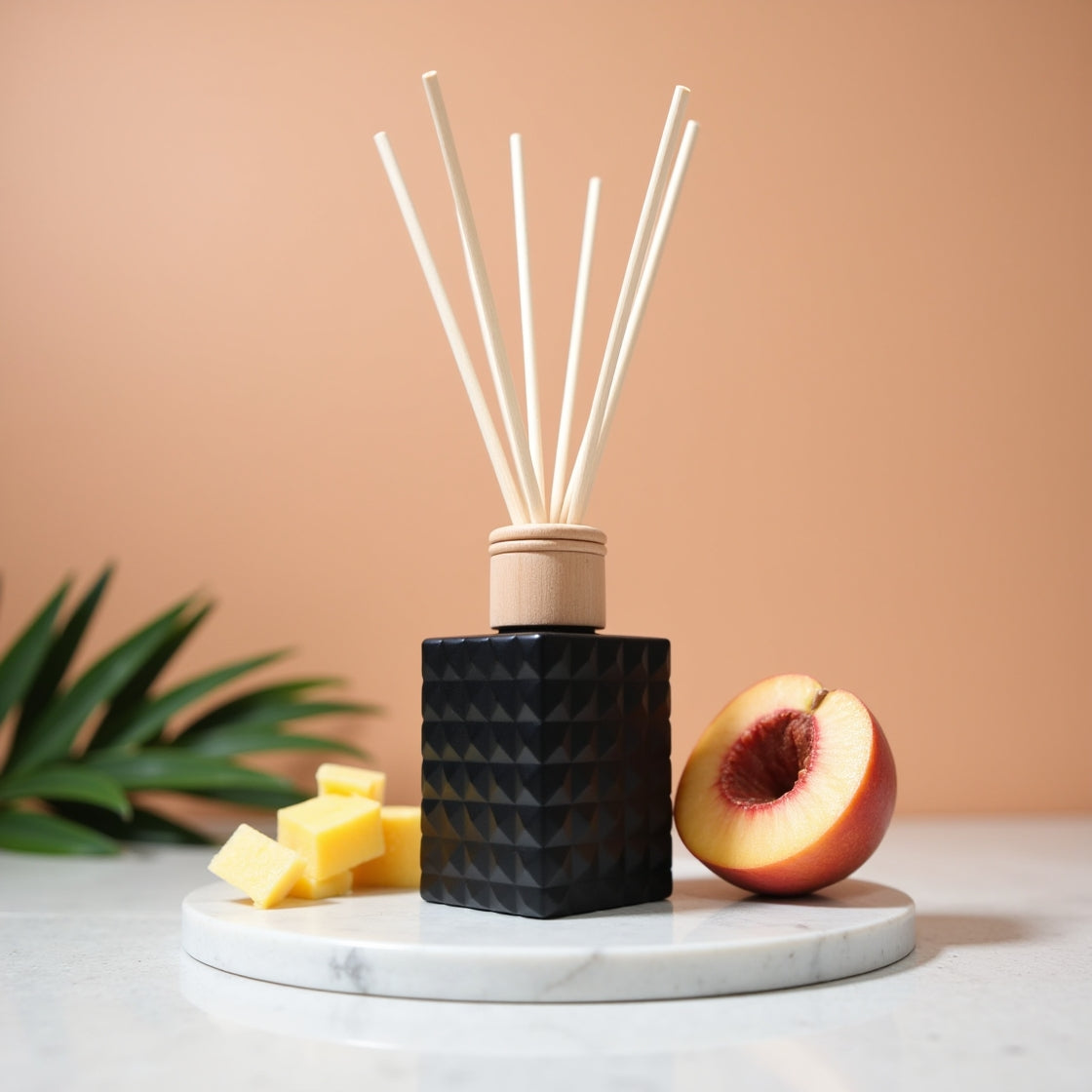 A fruity Pineapple & Peach scented reed diffuser in a matte black bottle.