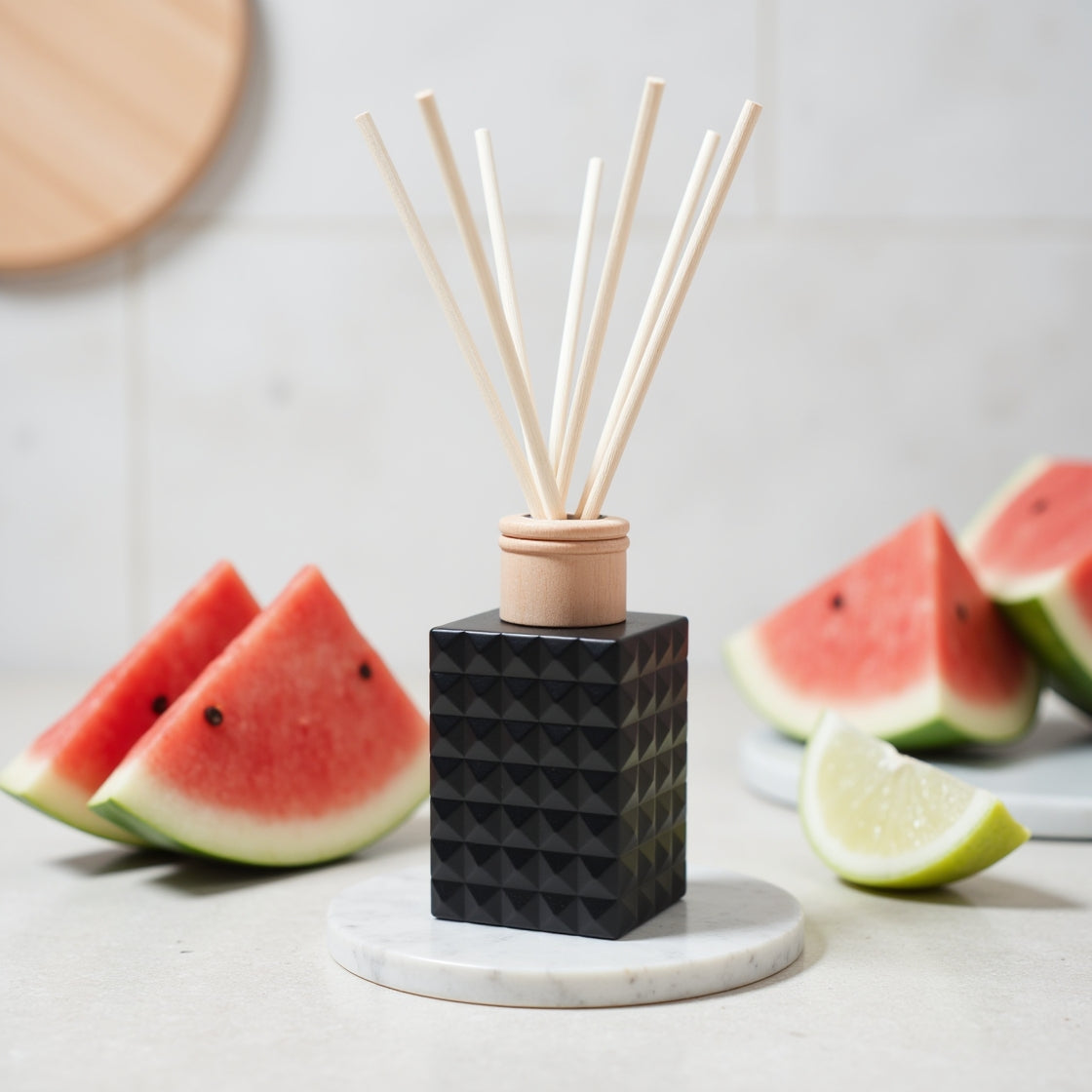 A juicy Summer Melon Spritzer scented reed diffuser in a matte black bottle.